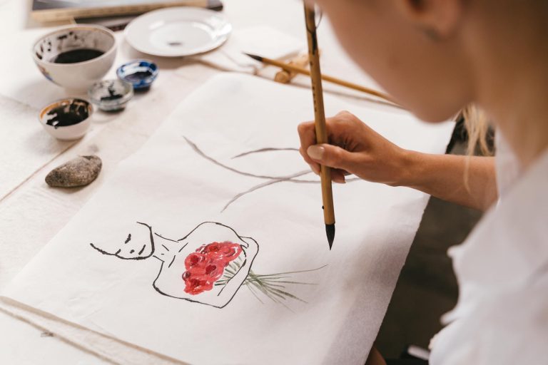 A woman artist delicately painting with a traditional brush, focusing on creativity and craftsmanship.