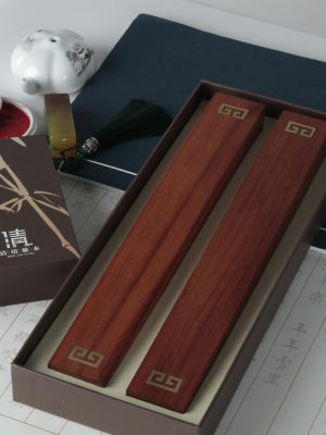 Elegant Chinese calligraphy set with ink, brushes, and wooden blocks on a paper background.