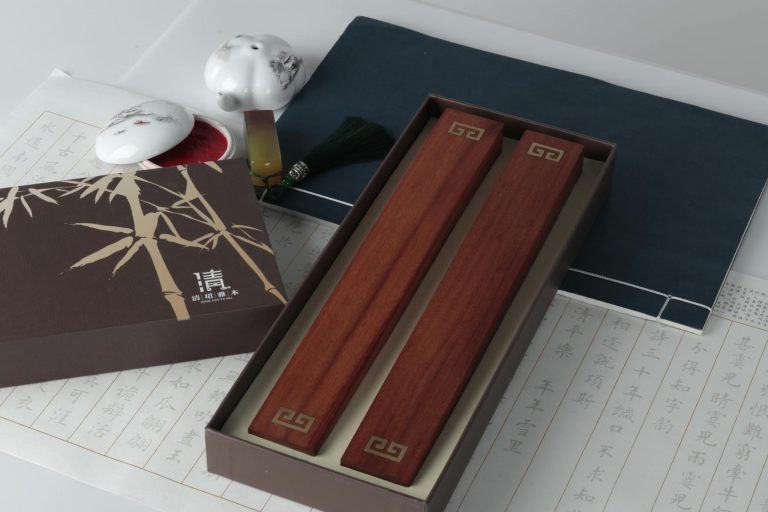 Elegant Chinese calligraphy set with ink, brushes, and wooden blocks on a paper background.